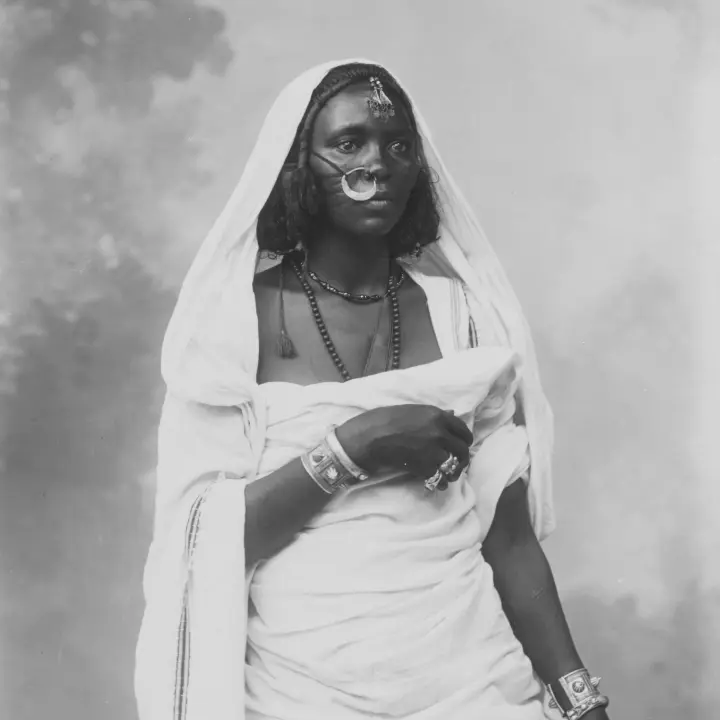 Portrait d’une femme africaine vêtue d’un costume traditionnel, arborant des bijoux décoratifs.